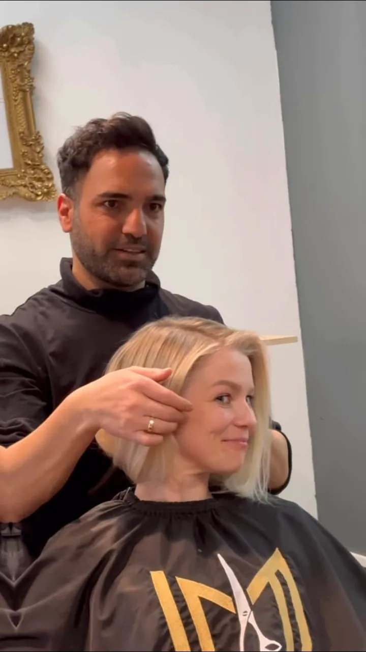 Yusuf stylt einer lächelnden Kundin den frisch geschnittenen Bob